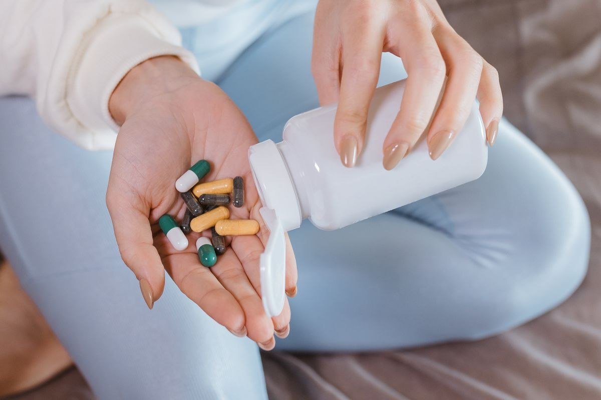Viên nang glucosamine đổ ra từ hũ đựng vào tay